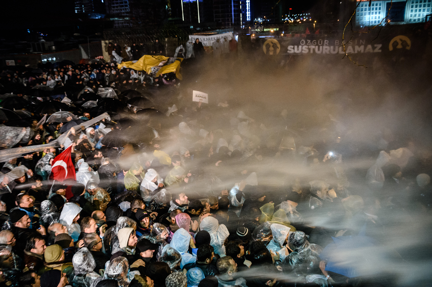 Turkish anti riot police officers launch water cannon and tear gas to disperse supporters of the Turkish Zaman Daily newspaper, who demonstrate outside the newspaper headquarters on March 4, 2016 in Istanbul.  An Istanbul court on March 4, 2016 ordered into administration a Turkish Zaman daily newspaper that is sharply critical of President Recep Tayyip Erdogan, amid growing alarm over freedom of expression in the country.  / AFP / OZAN KOSE